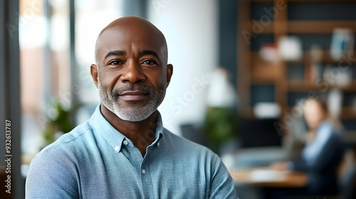 A confident man smiles in a modern office setting, exuding professionalism and approachability.