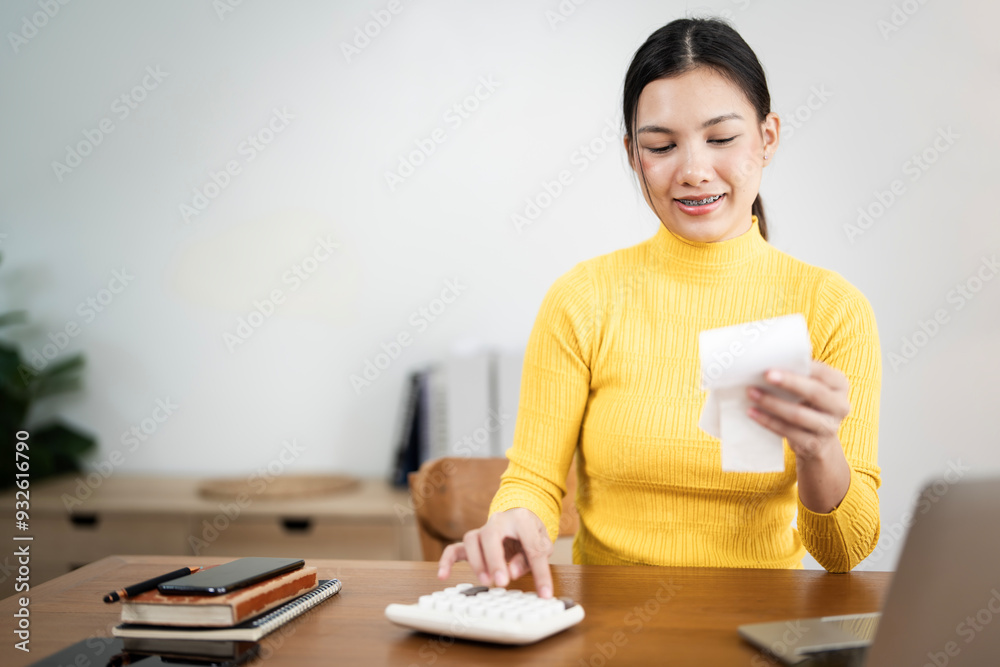 Happy young female work with financial papers at home count on calculator before paying taxes receipts Happy young female work with financial papers at home count on calculator before paying taxes receipts