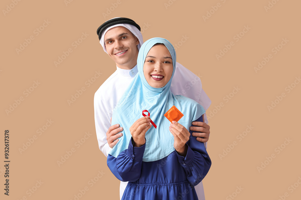 Beautiful Muslim couple with red ribbon and condom on brown background. AID awareness concept Beautiful Muslim couple with red ribbon and condom on brown background. AID awareness concept