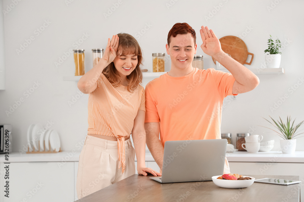 Young deaf mute couple video chatting with sign language in kitchen Young deaf mute couple video chatting with sign language in kitchen