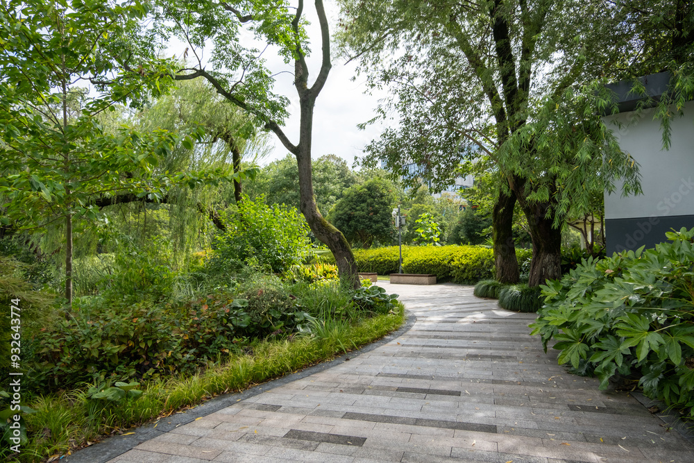 A serene and inviting outdoor space, well-maintained with manicured and trimmed hedges in urban parkland. A winding pathway leads through the park, with a variety of trees and shrubs A serene and inviting outdoor space, well-maintained with manicured and trimmed hedges in urban parkland. A winding pathway leads through the park, with a variety of trees and shrubs