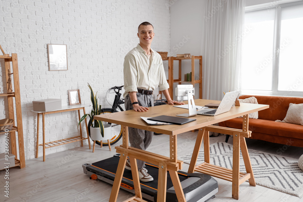 Young man training on treadmill at table in office Young man training on treadmill at table in office