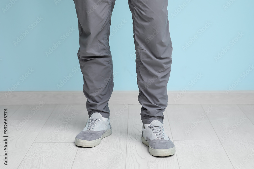 Young man in stylish sneakers near blue wall, closeup Young man in stylish sneakers near blue wall, closeup