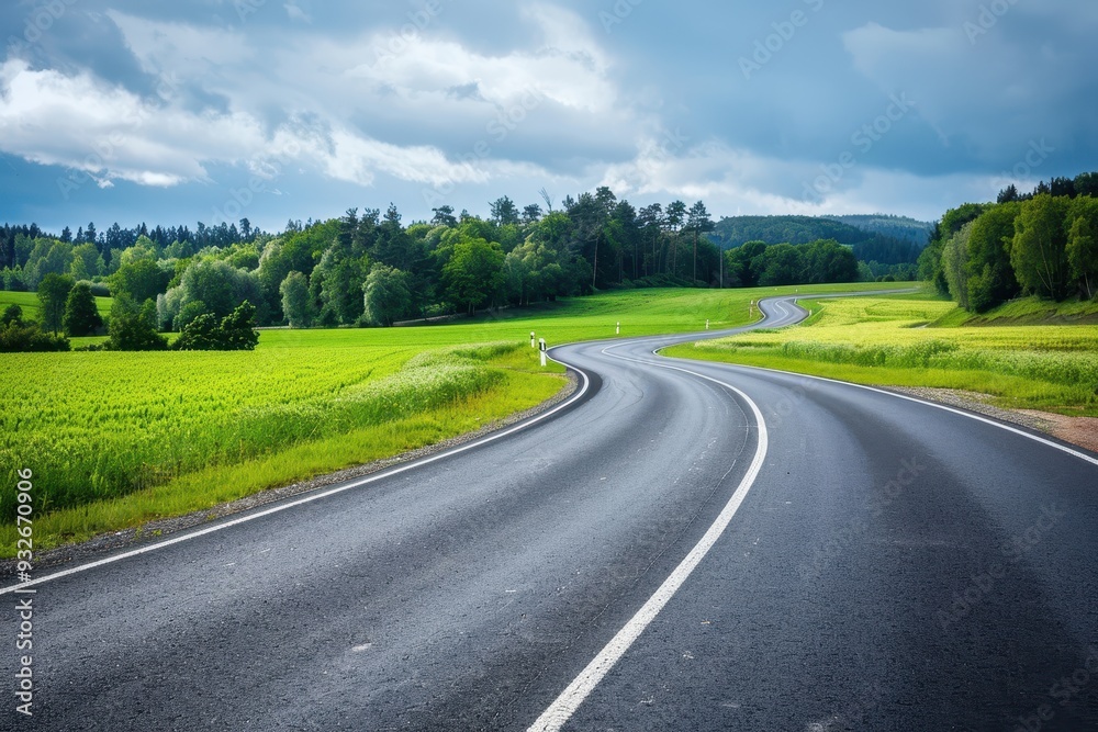 Horizontal frame capturing an asphalt road with white markings bordered by fields and trees Horizontal frame capturing an asphalt road with white markings bordered by fields and trees