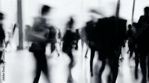 Black and white blurred motion image of business professionals standing and walking in a lobby
