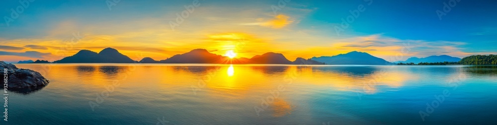 Obraz premium Panoramic Sunrise Over Island with Mountains in Thailand Reflecting Vibrant Colors on Calm Waters, Peaceful Natural Beauty Scene