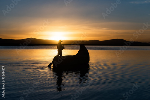 Fototapeta Naklejka Na Ścianę i Meble -  Man in traditional costume sailing in a traditional boat on lake titicaca at sunset puno peru