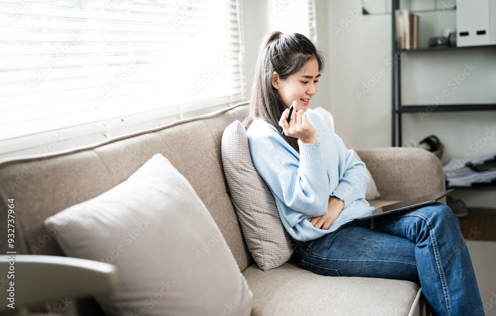 Smiling young woman sitting on cozy couch at home, using digital tablet, happy girl looking at computer screen, freelancer working online Smiling young woman sitting on cozy couch at home, using digital tablet, happy girl looking at computer screen, freelancer working online