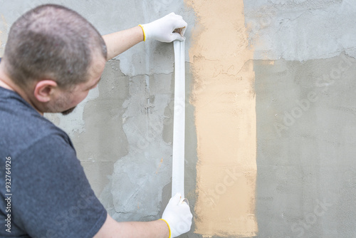 A man is painting a wall with a white stripe photo