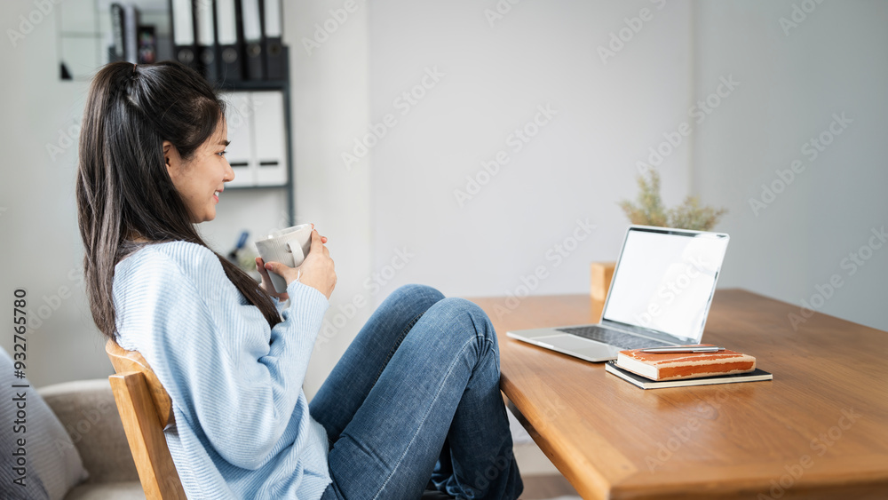 young pleased happy cheerful cute beautiful business woman sit indoors in home office, drinkinf coffee and using laptop computer young pleased happy cheerful cute beautiful business woman sit indoors in home office, drinkinf coffee and using laptop computer