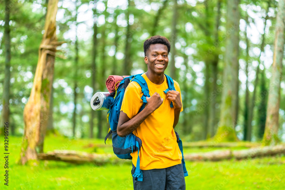 Fototapeta premium A Young african man hiking through green forest