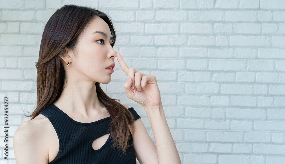Portrait smile confident asian designer woman black top office look. Finger point at nose, plastic surgery clinic on white wall with copy space Portrait smile confident asian designer woman black top office look. Finger point at nose, plastic surgery clinic on white wall with copy space