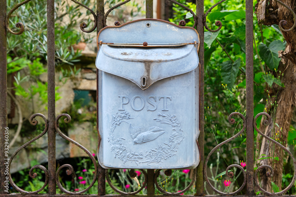 Fototapeta premium Beautiful old light blue and weathered metal mailbox or letterbox with the word post and an image of a swallow on an old fence in Cornac Lot Occitanie in Southern France