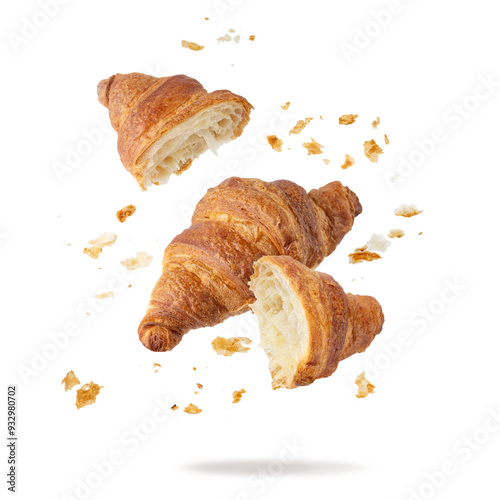 Fresh baked butter breakfast croissants and crumbs falling flying isolated on white background. Whole and broken in half croissants.