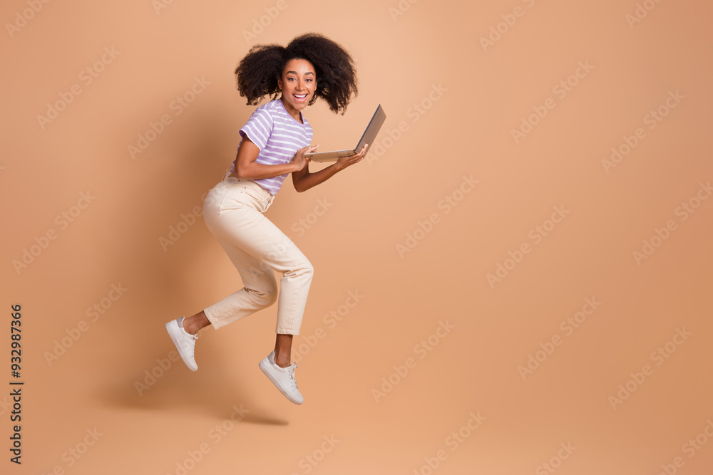 Full length portrait of pretty young woman jump run hold laptop wear t-shirt isolated on beige color background Full length portrait of pretty young woman jump run hold laptop wear t-shirt isolated on beige color background