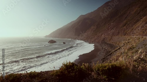 Black sand beach with big waves during sunset in a scenic ocean bay.