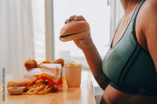 Binge eating disorder concept with woman eating fast food burger, fired chicken , donuts and desserts photo