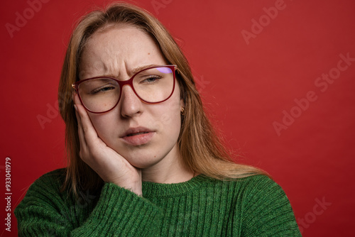 portrait of a girl with a toothache on a red background, toothache concept