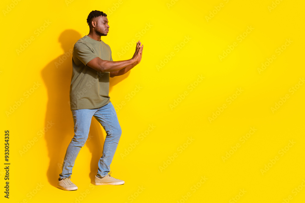 Photo of handsome strong attractive man wear trendy khaki clothes push empty space isolated on yellow color background