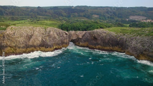 Aerial view of a scenic natural arch in a rocky coastline landscape in Llanes, Asturias, Spain. High quality 4k footage photo