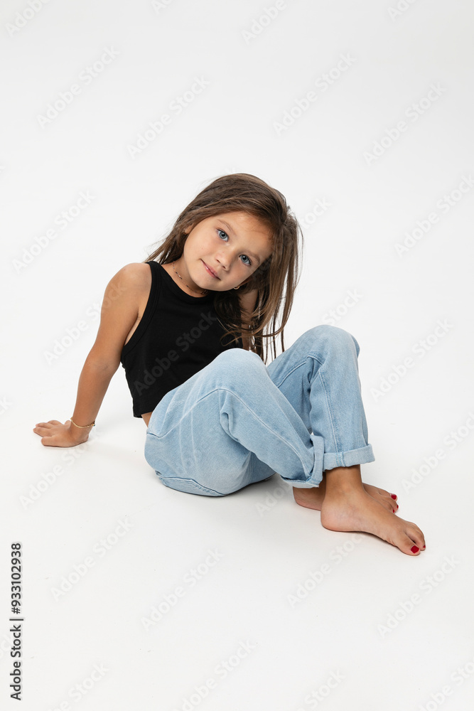 Fashionable little cute girl posing down on the floor, looking at the camera, over white background. Fashionable little cute girl posing down on the floor, looking at the camera, over white background.