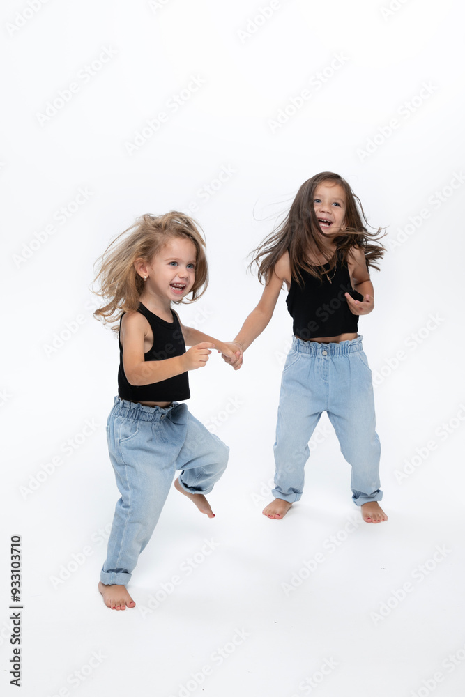 Full lengrth image of a two little girls dancing in studio, dressed in a black tops and jeans, isolated white background. Full lengrth image of a two little girls dancing in studio, dressed in a black tops and jeans, isolated white background.