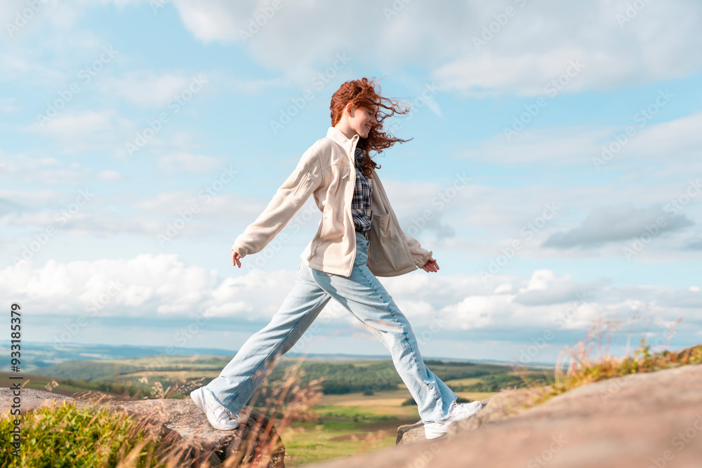 Fototapeta premium Woman Gracefully Walks on Rocky Terrain Against a Backdrop of Rolling Hills During Daytime