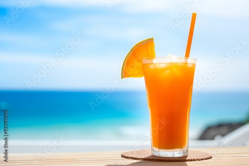 Glass of orange juice on wooden table on the beach, blue seashore background