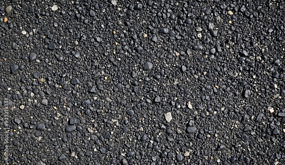 Close-up of a dark, textured surface with small black pebbles and coarse gravel. Close-up of a dark, textured surface with small black pebbles and coarse gravel.