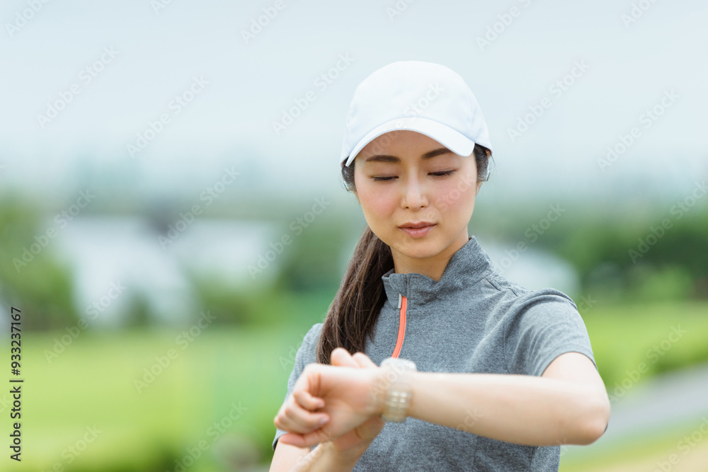 スマートウォッチを見てランニングをする女性