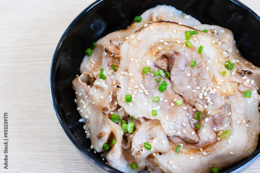 Donburi rice topped with chashu pork slices in a black bowl. Donburi rice topped with chashu pork slices in a black bowl.