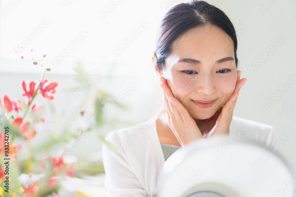 鏡を見てスキンケアをする女性（ビューティーイメージ）