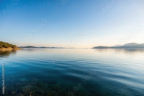 Tranquil lake reflecting a serene blue sky and distant hills