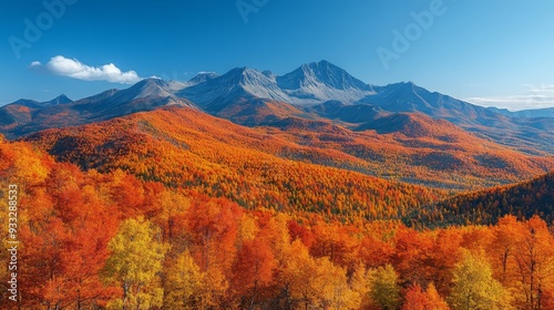 Vibrant autumn colors display across a mountain range under a clear blue sky