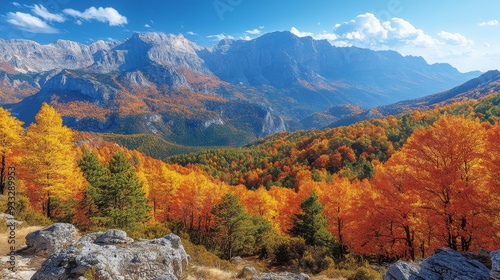 Vibrant autumn foliage surrounds a majestic mountain range under clear blue skies
