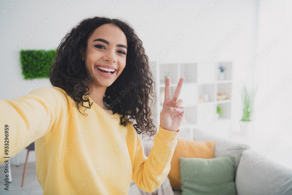 Selfie of happy positive young american girl wearing yellow shirt making video vlog lifestyle at home showing v sign peace symbol Selfie of happy positive young american girl wearing yellow shirt making video vlog lifestyle at home showing v sign peace symbol