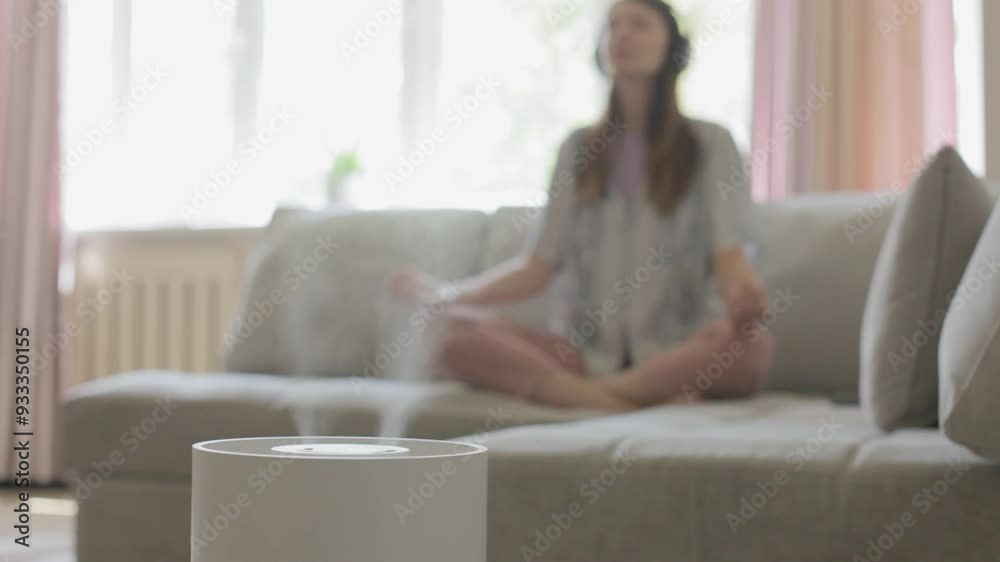 Air humidifier during relax, blurred young woman meditating with headphones. Air humidifier during relax, blurred young woman meditating with headphones.