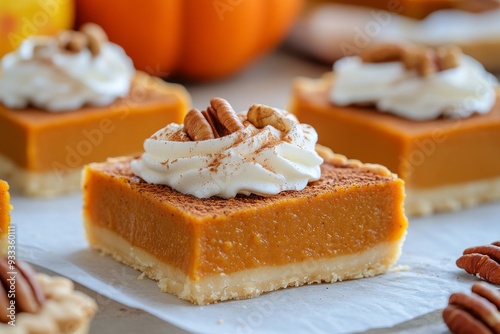 Pumpkin dessert bars topped with whipped cream and cinnamon in a cozy fall se...
