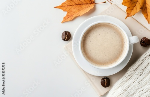 Cozy coffee cup with latte art beside autumn leaves and book in soft lighting