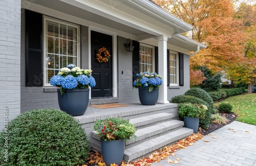 Colorful flower pots adorn the steps of a gray house during autumn in a subur...