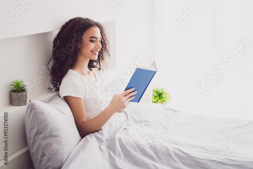 Photo of charming young woman lying bed read book good morning vibes awake home bedroom light white interior