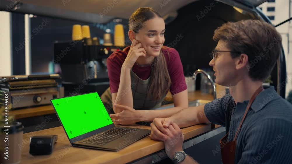 Street Cafe Manager and Female Barista Using Laptop Computer with Green Screen Mock Up Display at a Food and Coffee Truck, Discussing Business Strategies and Financial Reports Street Cafe Manager and Female Barista Using Laptop Computer with Green Screen Mock Up Display at a Food and Coffee Truck, Discussing Business Strategies and Financial Reports