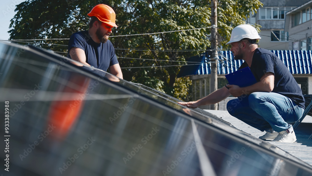 Professional engineers inspect solar panel installation on a rooftop under sunlight. Detailed check of the solar system setup for efficiency and quality. Professional engineers inspect solar panel installation on a rooftop under sunlight. Detailed check of the solar system setup for efficiency and quality.