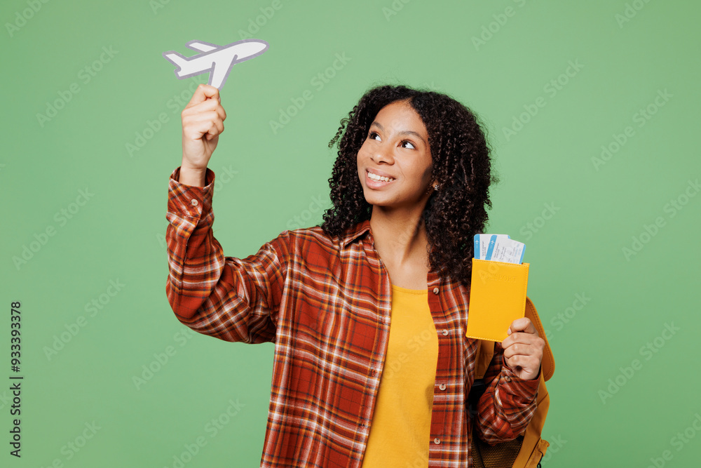Young fun teen girl student wear brown yellow casual clothes backpack bag hold airplane mockup passport ticket, travel abroad isolated on plain green background High school university college concept Young fun teen girl student wear brown yellow casual clothes backpack bag hold airplane mockup passport ticket, travel abroad isolated on plain green background High school university college concept