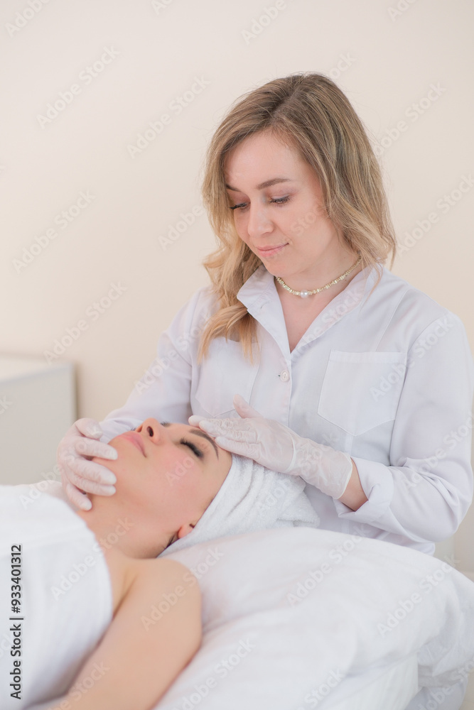 Cosmetologist does massage to brunette lady client by hands in beauty salon office close view . Cosmetologist does massage to brunette lady client by hands in beauty salon office close view .