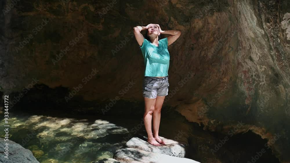 Woman exploring cave, standing on rock with arms raised, embracing nature and outdoor adventure in tranquil setting, expressing freedom and joy in scenic environment Woman exploring cave, standing on rock with arms raised, embracing nature and outdoor adventure in tranquil setting, expressing freedom and joy in scenic environment