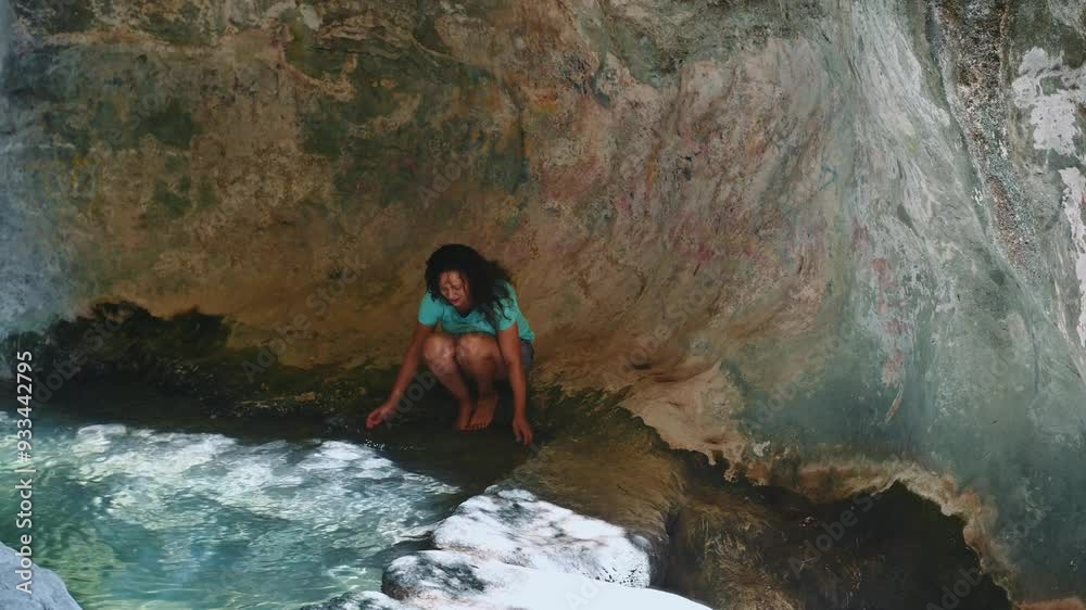 Woman relaxing by a natural rock pool surrounded by stone formations and sunlight, enjoying the tranquility and connection to nature in a serene secluded spot Woman relaxing by a natural rock pool surrounded by stone formations and sunlight, enjoying the tranquility and connection to nature in a serene secluded spot