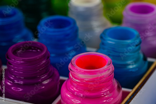 A vibrant display of various colored ink bottles arranged in a grid pattern, showcasing a spectrum of bright and vivid hues. The image highlights the rich and diverse palette of colors for art.