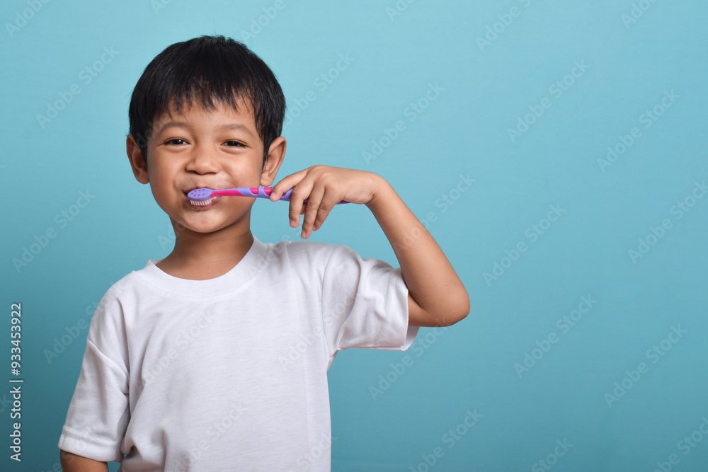 A happy Asian boy with clean teeth brushing his teeth isolated on blue background. Children's dental hygiene, Medical care A happy Asian boy with clean teeth brushing his teeth isolated on blue background. Children's dental hygiene, Medical care