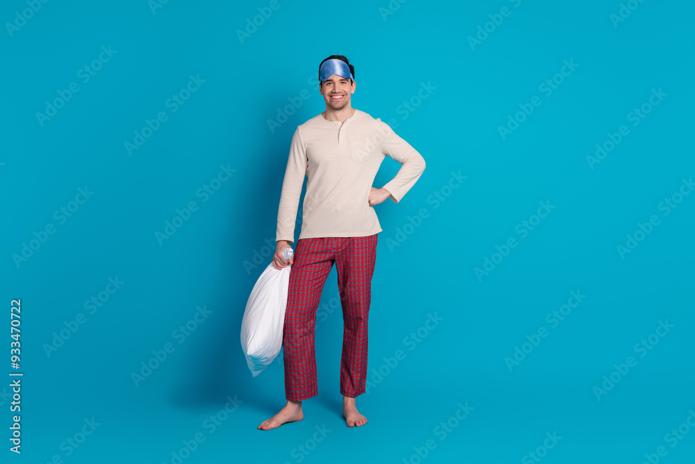 Full size photo of nice young man hold pillow empty space wear pajama isolated on blue color background